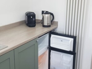 A kitchenette with a Bosch coffee maker, a GEERNS kettle, and a black refrigerator.