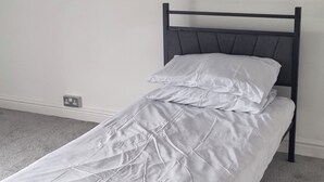 A single bed with a headboard, white bedding, and a power outlet on the wall. - Ehen Cottage (Cleator Moor)