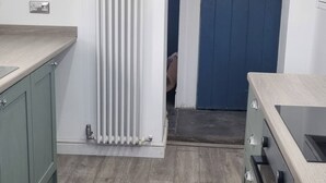 Una cocina con un radiador, una puerta azul y una encimera de color claro.