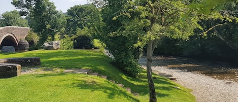 A stone bridge, a grassy area, and a tree.