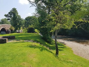A stone bridge, a grassy area, and a tree.