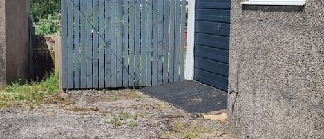 A gated driveway leading to a garage with a concrete pathway and a small drainage grate.