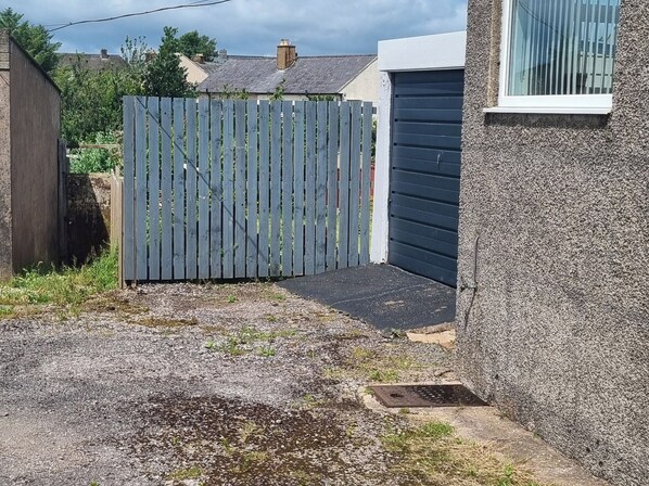 A gated driveway leading to a garage with a concrete pathway and a small drainage grate.
