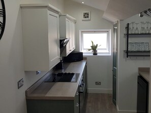 A modern kitchen with white cabinets, a black microwave, and a window with a plant.