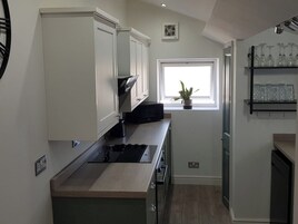 Una cocina moderna con armarios blancos, un microondas negro y una ventana con una planta.
