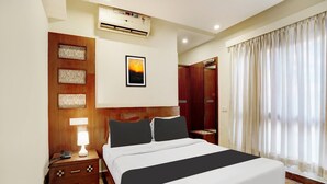 A hotel room with a bed, bedside table, lamp, air conditioning unit, artwork, and a wardrobe. - Suite La Casa Boutique Koramangala (Bengaluru)