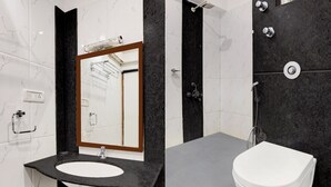A modern bathroom with a marble vanity, a white sink, a mirror, a shower area, and a toilet. - Suite La Casa Boutique Koramangala (Bengaluru)