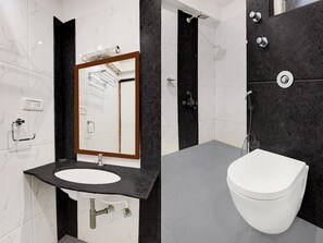Ein modernes Badezimmer mit Waschtisch aus Marmor, einem weißen Waschbecken, einem Spiegel, einer Duschkabine und einer Toilette.