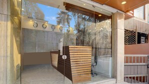 A modern reception area with a glass partition, a wooden reception desk, and a visible staircase leading to an upper level. - Suite La Casa Boutique Koramangala (Bengaluru)