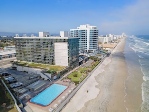 Ein modernes Hotel mit Pool und direktem Zugang zum Strand, das eine Mischung aus Glas- und Betonarchitektur zeigt.