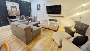 A modern living room with a sectional sofa, a TV, a coffee table, and a dining area with chairs.