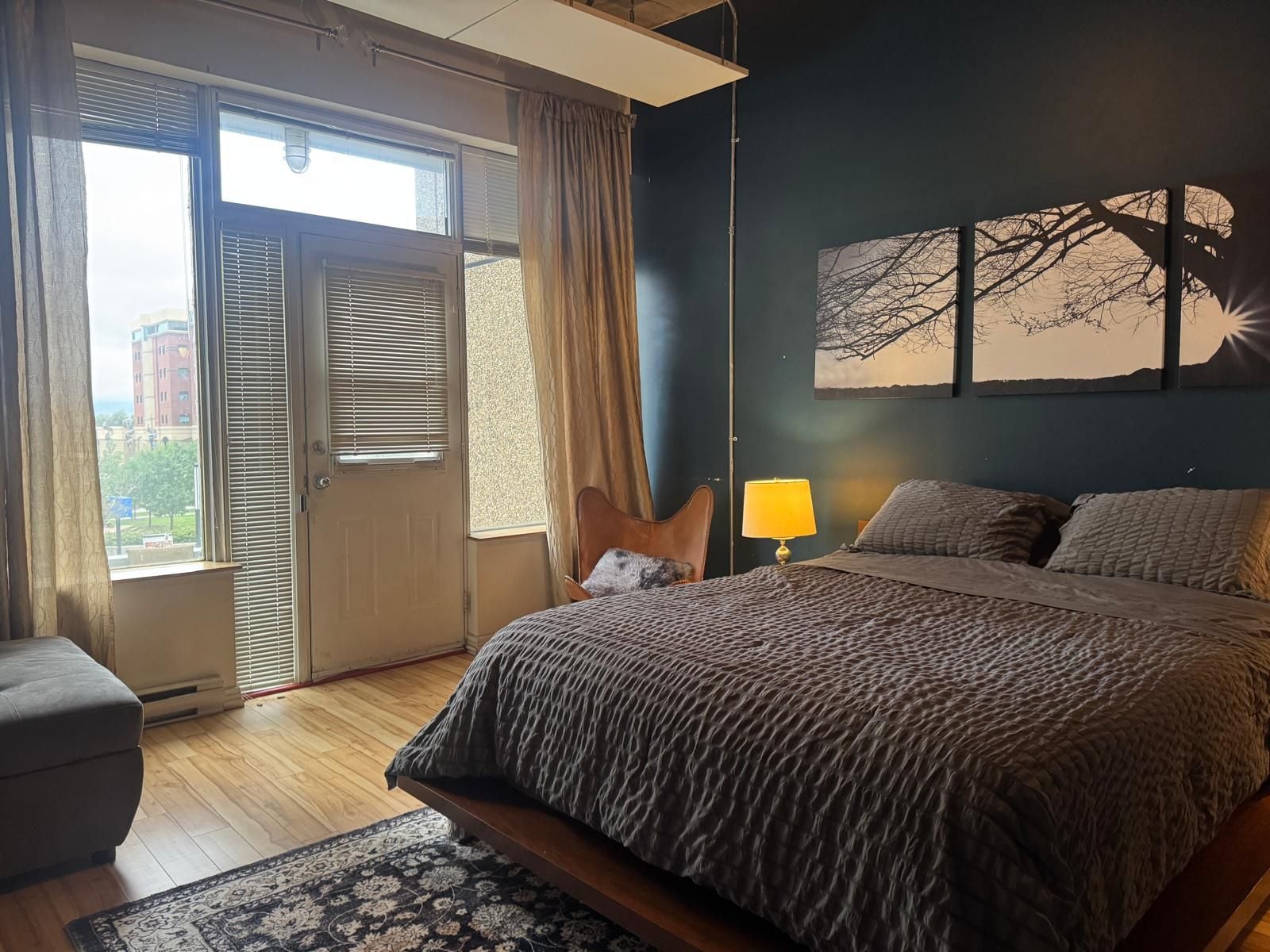 A bedroom with a bed, a chair, a lamp, and a window with blinds.