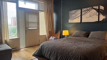 A bedroom with a bed, a chair, a lamp, and a window with blinds.