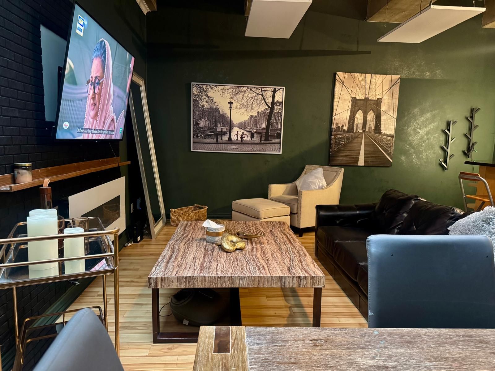 Una sala de estar con televisor, una mesa de centro, un sofá y dos cuadros en la pared.