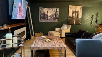 Una sala de estar con televisor, una mesa de centro, un sofá y dos cuadros en la pared.