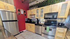 A modern kitchen with stainless steel appliances, wooden cabinets, and a red accent wall.