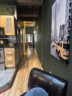Un pasillo estrecho con una zona de cocina a la izquierda, un comedor en el centro y un gran mural con vistas a la ciudad a la derecha.
