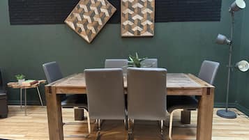 Un comedor con una mesa de madera, cuatro sillas y dos obras de arte geométricas colgadas en la pared.