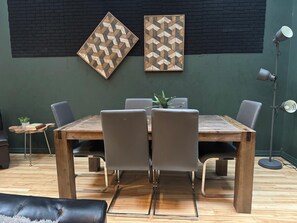 Un comedor con una mesa de madera, cuatro sillas y dos obras de arte geométricas colgadas en la pared.