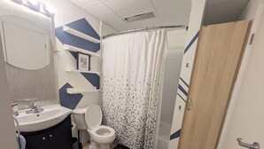 A bathroom with a sink, toilet, shower curtain, and a door.