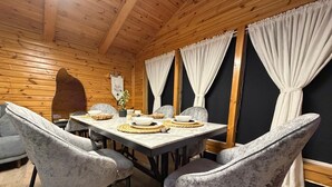 A wooden-paneled room with a dining table set for four, surrounded by upholstered chairs.