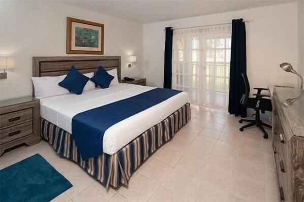 Una habitación de hotel con una cama grande, un escritorio, un aparador y una ventana con cortinas.