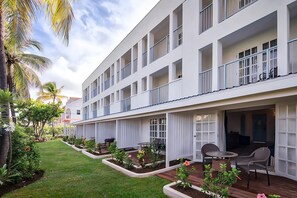 Un hotel moderno con varios balcones, un jardín cuidado y zonas de estar al aire libre.