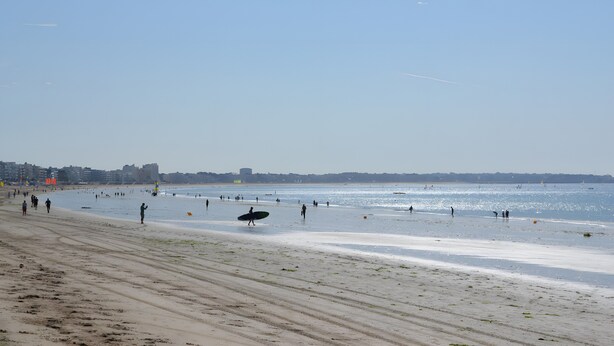 A beach with people walking and a surfboard on the sand. - Villa Pradel – Holiday Home Guérande La Baule, 4 Bedrooms, 7 Guests (Guérande)