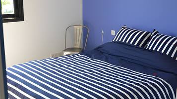 Une chambre à coucher avec un lit, une chaise, une fenêtre et une lampe.