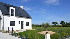 A modern two-story house with a black roof, white walls, and a fenced yard with a small tree and shrubs. - Villa Pradel – Holiday Home Guérande La Baule, 4 Bedrooms, 7 Guests (Guérande)