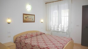 Una camera da letto con un letto, comodini, una finestra con tende, luci a parete e un quadro incorniciato.