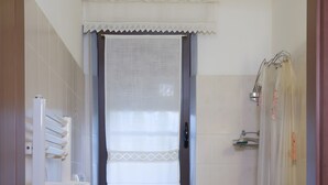 Un bagno piccolo con il water, bidet, lavandino e una finestra con tenda.