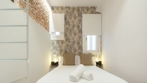 A hotel room with a bed, two nightstands, a window, and a brick wall. - Stay in Madrid for 5 Guests (Madrid)