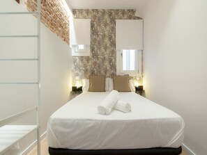 Ein Hotelzimmer mit einem Bett, zwei Nachttischen, einem Fenster und einer Ziegelwand.