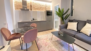 A modern living room with a grey sofa, two pink chairs, a glass coffee table, and a patterned rug. - Stay in Madrid for 5 Guests (Madrid)