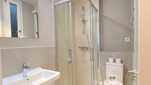 A bathroom with a glass-enclosed shower, a white sink, and a toilet. - Stay in Madrid for 5 Guests (Madrid)