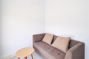 A corner room with a brown sofa, two pillows, and a small round table. - Elegant Deluxe DBL Retreat Near Mangusada Hospital (Mengwi)
