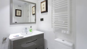 A modern bathroom with a white sink, a large mirror, framed pictures, a towel rack, and a toilet. - 6-guest Haven Near Golden Mile (Madrid)