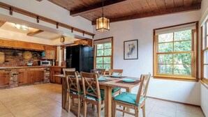 A spacious kitchen with wooden cabinets, a large island, and a dining area with wooden chairs and a table. - 109 GATED Urban LA cottage (Los Angeles)