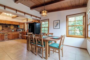 A spacious kitchen with wooden cabinets, a large island, and a dining area with wooden chairs and a table. - 109 GATED Urban LA cottage (Los Angeles)