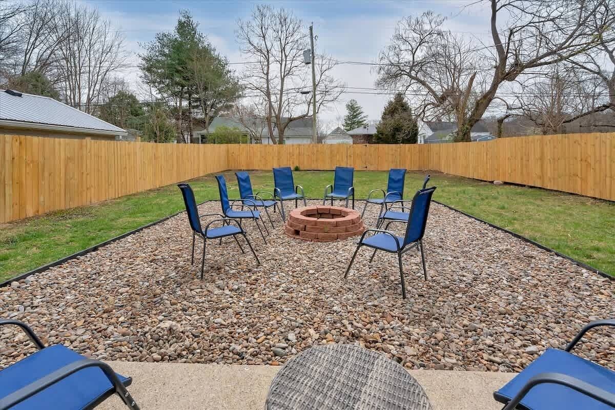 Ein Garten mit Feuerstelle, blauen Stühlen und einem Tisch.