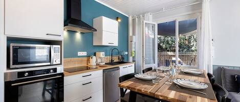 A modern kitchen with white cabinets, a black range hood, and a wooden dining table set for four.