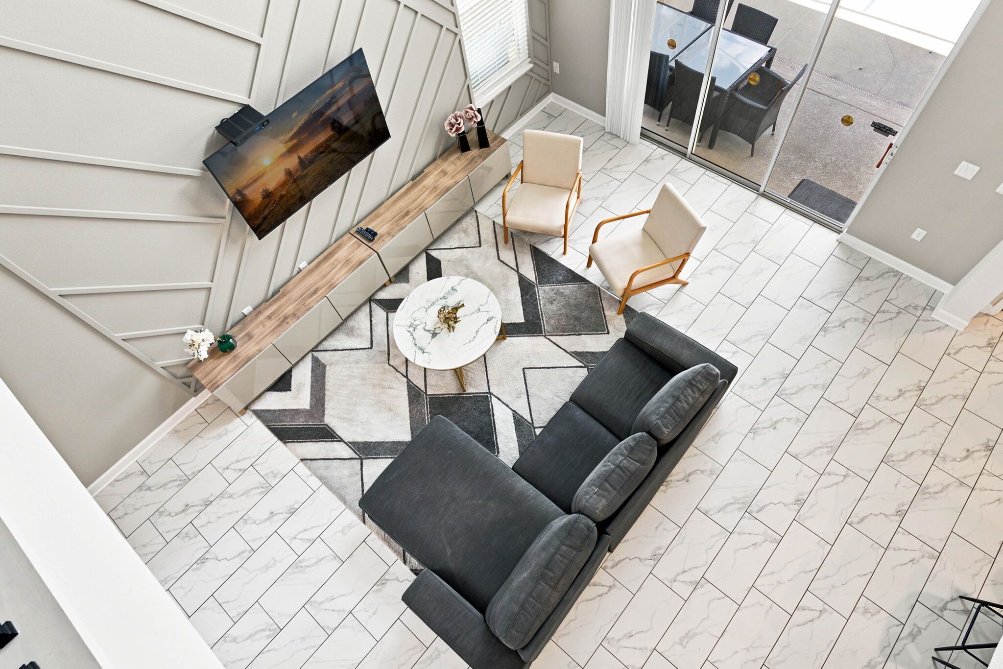 Uma sala de estar moderna com sofá, cadeiras, mesa de centro e TV fixada na parede.