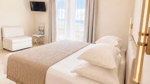 Ein Hotelzimmer mit Bett, Fernseher, einem kleinen Tisch und einem Fenster mit Vorhängen.