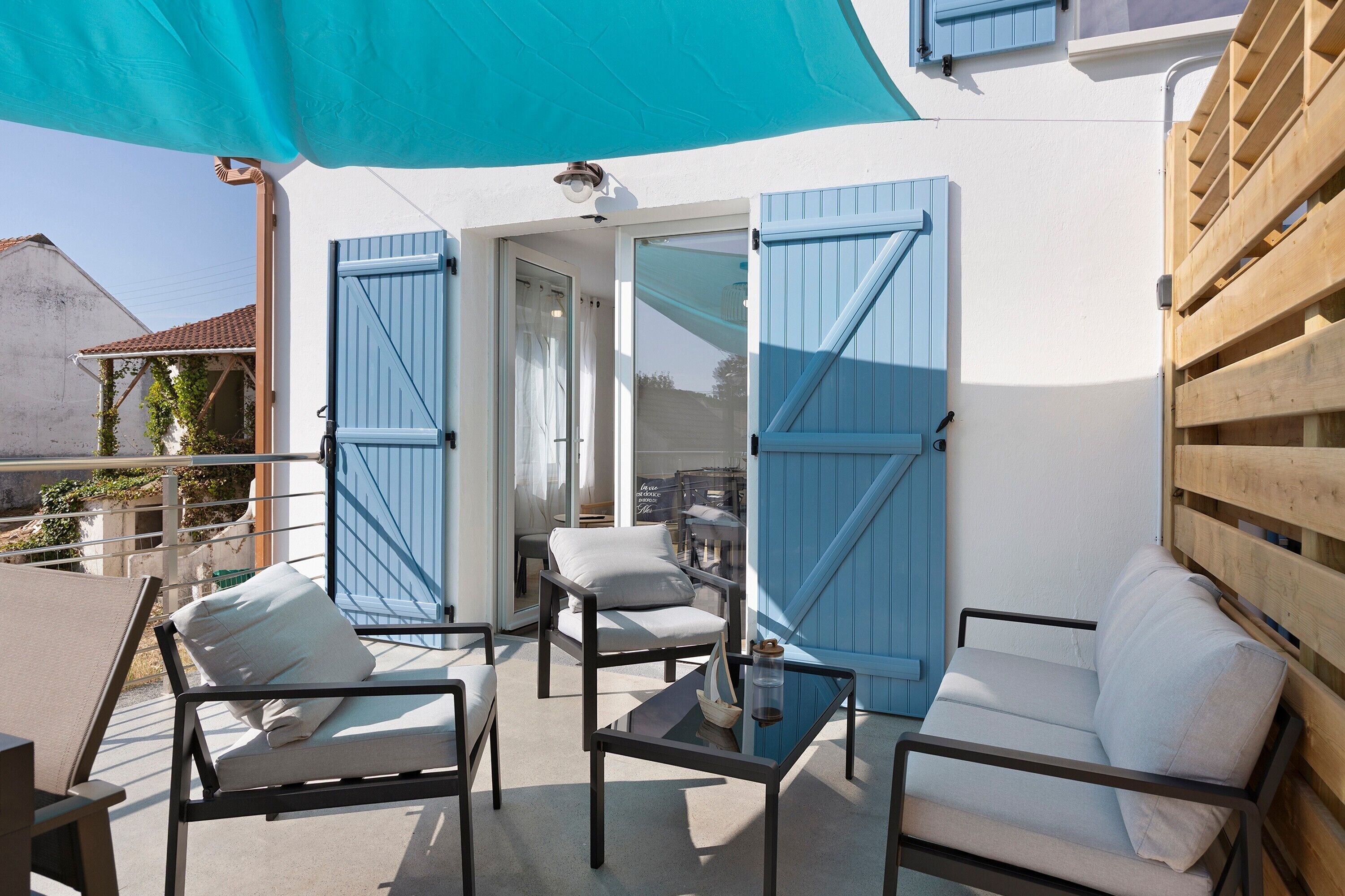 An outdoor seating area with a table, chairs, and a blue awning.
