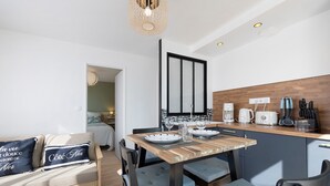 A modern kitchen with a wooden table, chairs, and a built-in oven. - Holiday Home 'L'oeillet Bleu' with Private Terrace, Wi-Fi and Air Conditioning (Saint-Jean-de-Monts)