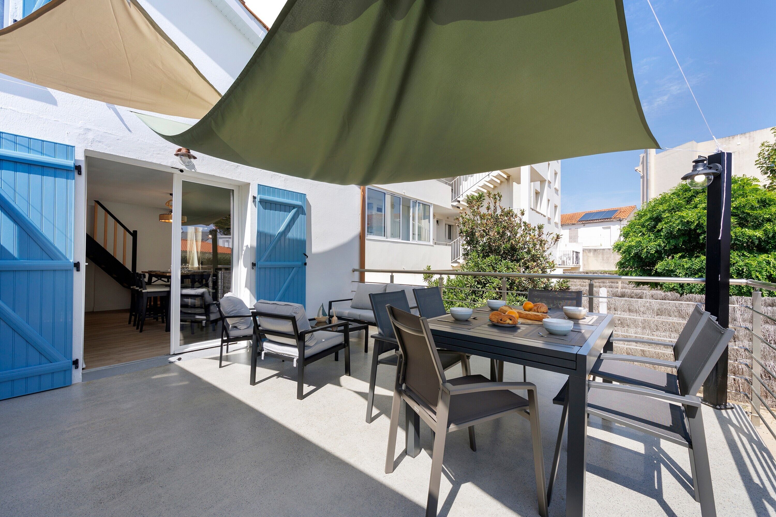 Une terrasse extérieure avec une table, des chaises et un grand parasol.