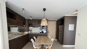 A modern kitchen with a central island, white chairs, and pendant lighting. - Vina del Mar 2BR sea views & balcony (Viña del Mar)