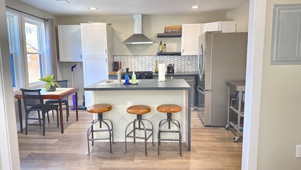 Eine moderne Küche mit Kochinsel, Barhocker und einem Essbereich mit Tisch und Stühlen.