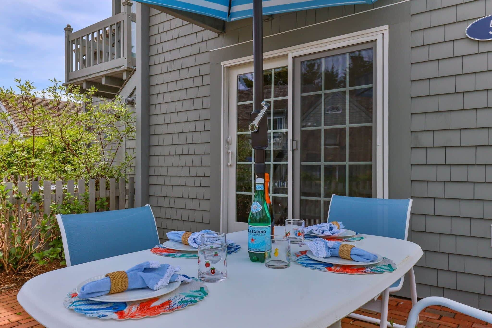 Une table de patio, avec une bouteille de bière, des verres et des chaises bleues.